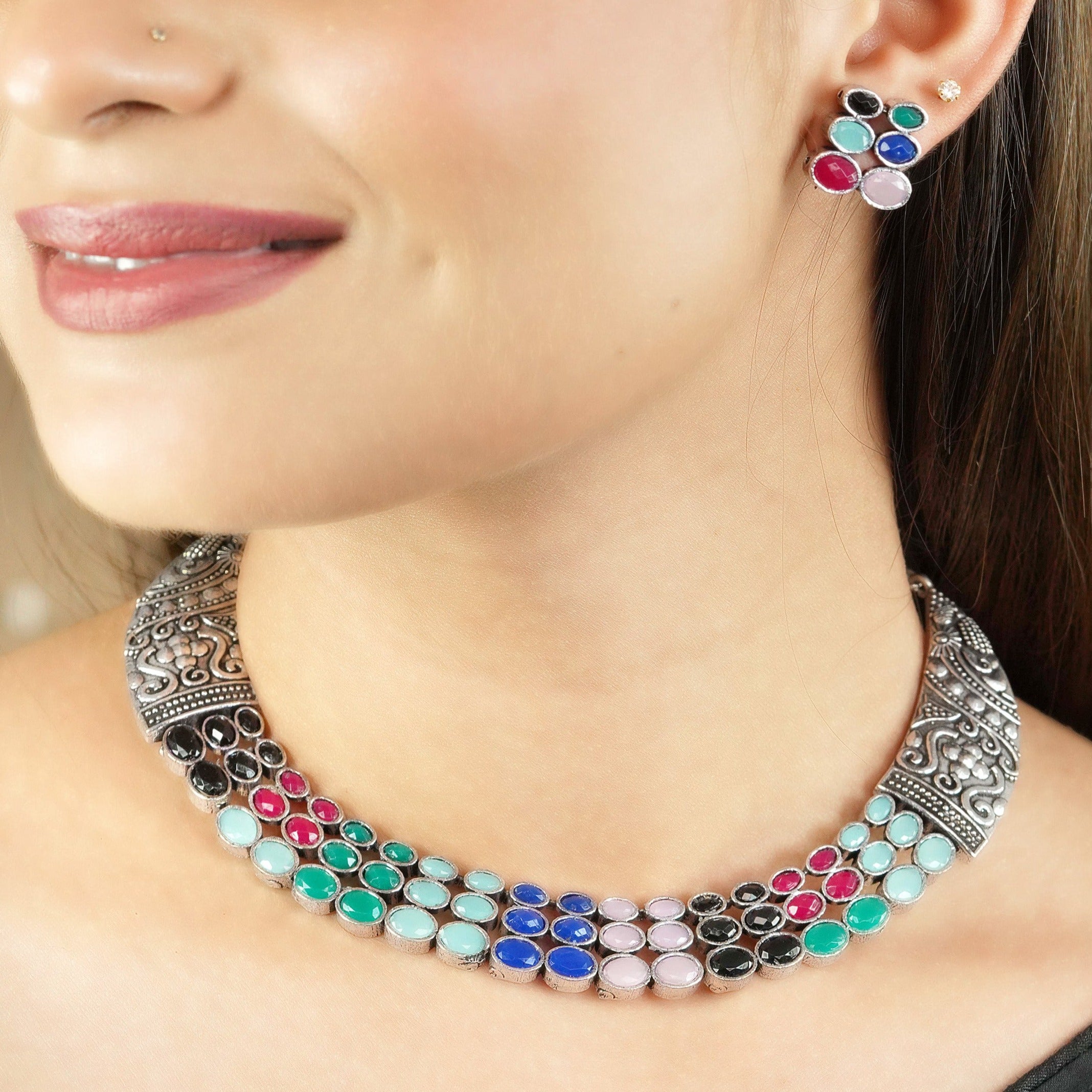 A woman wearing a colorful gemstone choker necklace and matching earrings.