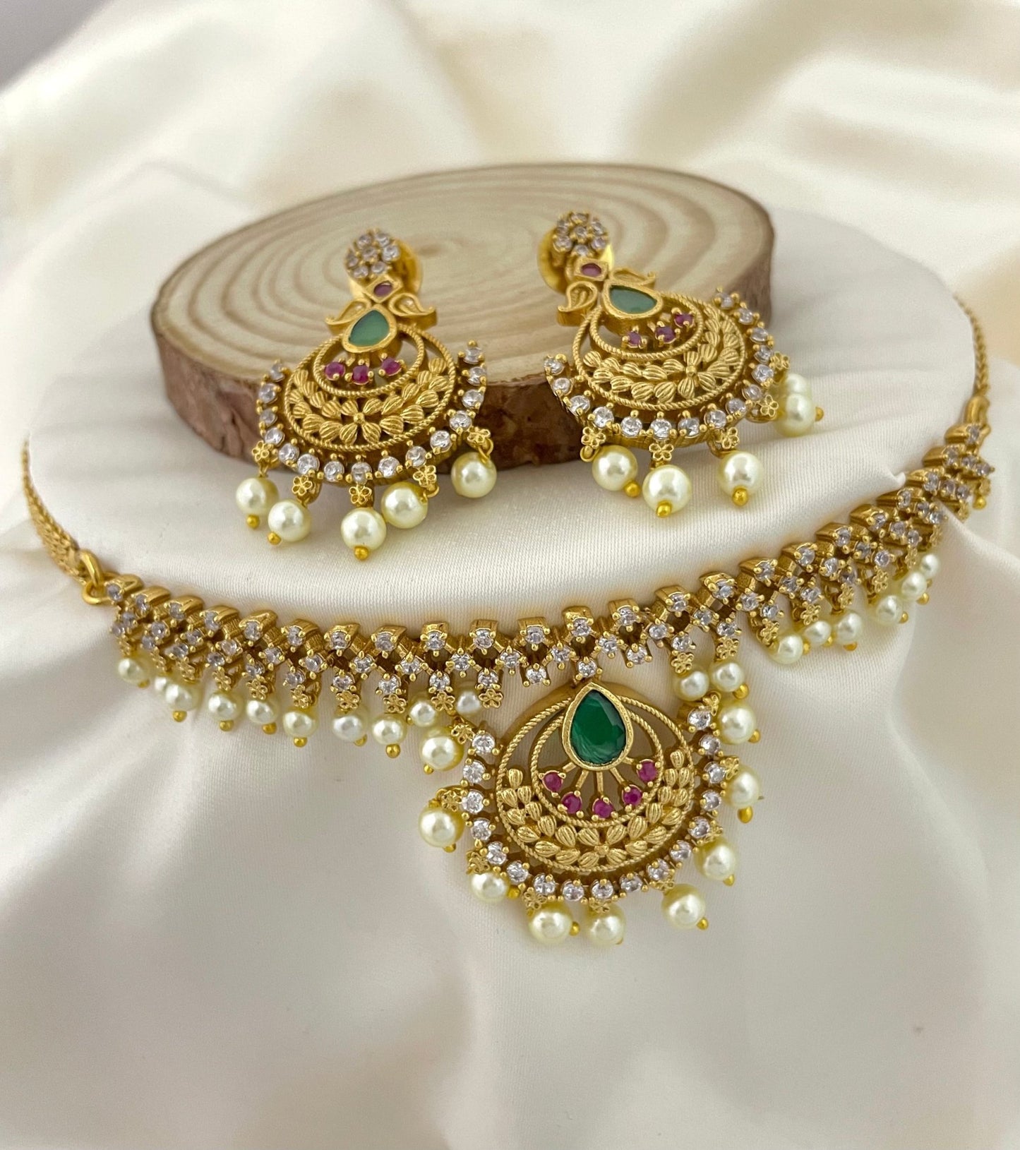 Gold choker necklace with matching earrings, adorned with pearls, green and pink gemstones, and American diamonds.