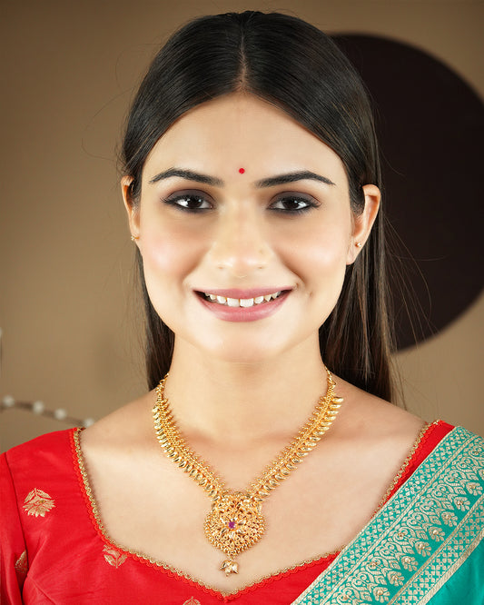 A woman wearing a traditional gold necklace with intricate designs and a red and green saree.