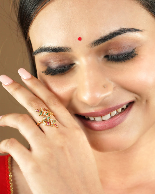 A woman wearing a gold ring with colorful gemstones shaped like leaves.