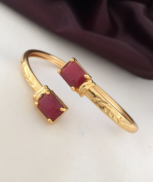Gold bracelet with two rectangular red gemstones.