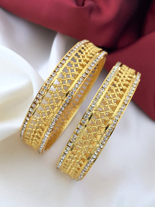 Two intricately designed gold bangles adorned with small diamonds.