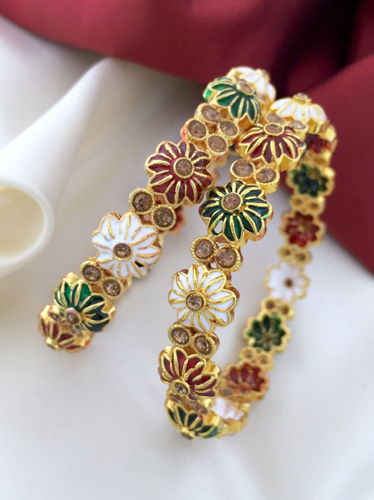 Two gold bangles adorned with colorful floral designs and embedded gemstones.