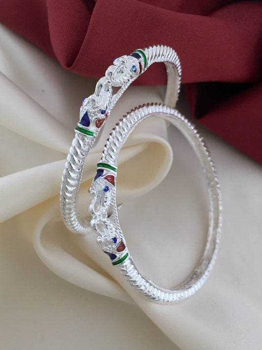 Two intricately designed silver bangles with colorful enamel detailing.