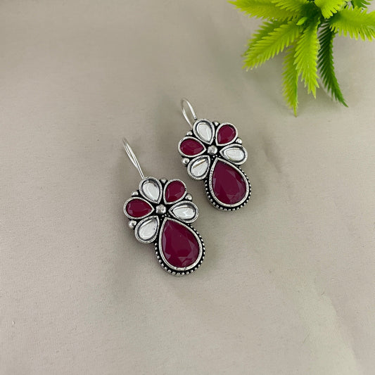A pair of silver earrings with red and white gemstones.