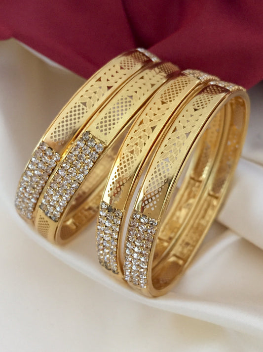Three gold bangles with intricate patterns and encrusted with small diamonds.