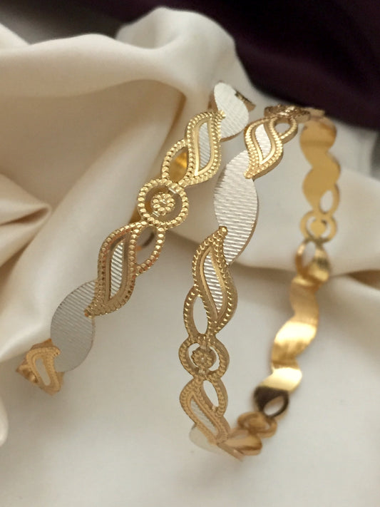 Two gold bracelets with intricate designs and white accents.
