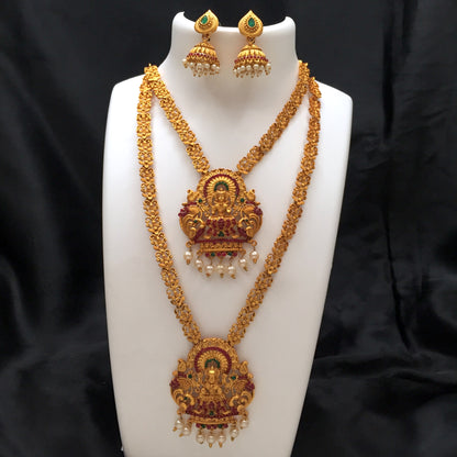 Gold temple jewelry set with intricate designs, featuring two layered necklaces and matching earrings adorned with pearls and green gemstones.