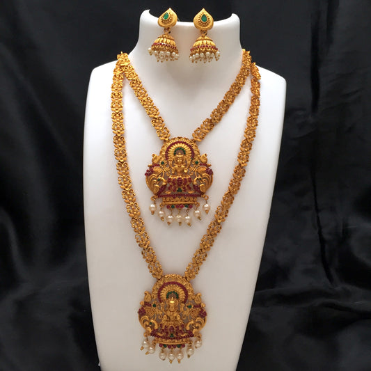 Gold temple jewelry set with intricate designs, featuring two layered necklaces and matching earrings adorned with pearls and green gemstones.