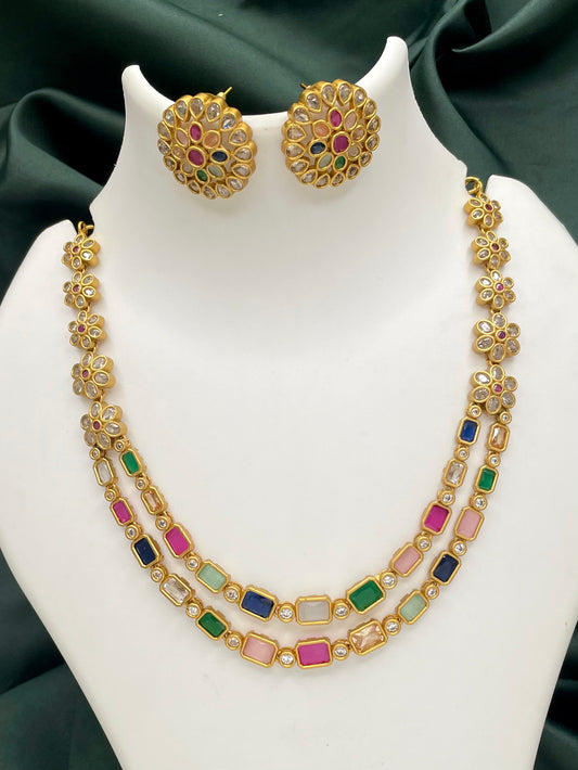 A gold necklace with multicolored gemstones and matching round earrings.