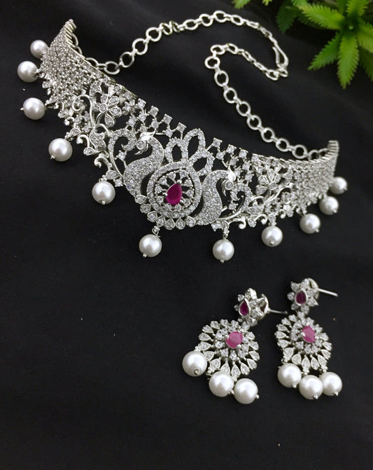 Silver choker necklace with ruby stone and matching earrings adorned with pearls and diamonds.