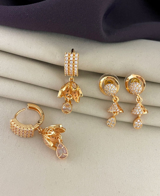 Three pairs of gold earrings with intricate designs and embedded gemstones.